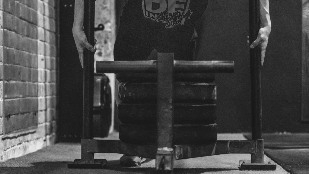 Persona levantando peso en gimnasio, esfuerzo físico para la competición de HYROX.