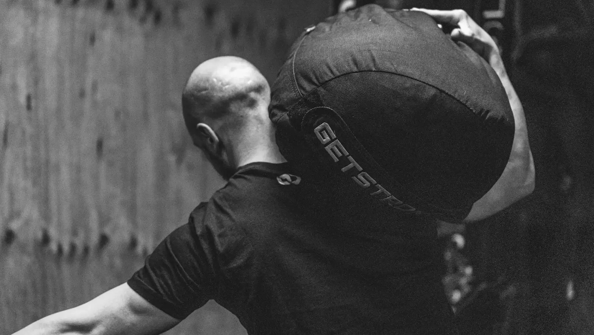 Ejercicio de CrossFit con saco de arena, entrenamiento de fuerza y resistencia.